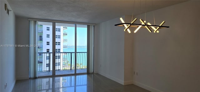 empty room featuring a notable chandelier, baseboards, a textured ceiling, and floor to ceiling windows