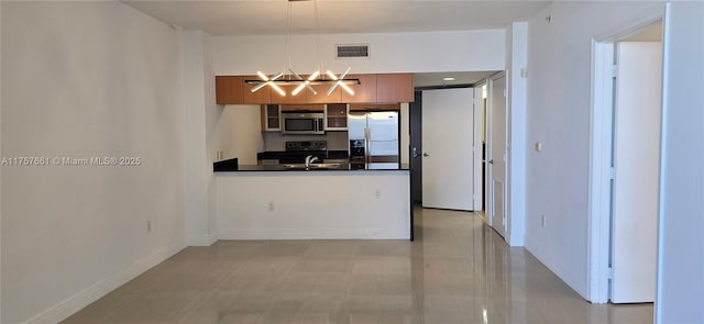 kitchen with visible vents, a peninsula, stainless steel appliances, dark countertops, and brown cabinets