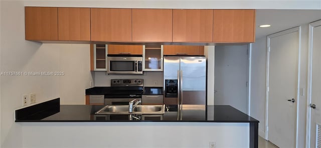 kitchen featuring a peninsula, recessed lighting, a sink, appliances with stainless steel finishes, and dark countertops