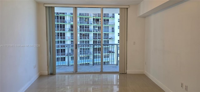 tiled spare room featuring a wall of windows and baseboards