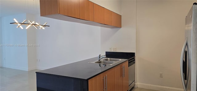 kitchen with dark countertops, freestanding refrigerator, baseboards, and a sink