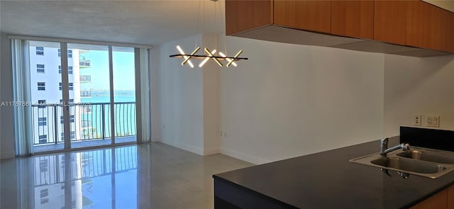 kitchen featuring dark countertops, baseboards, floor to ceiling windows, brown cabinets, and a sink