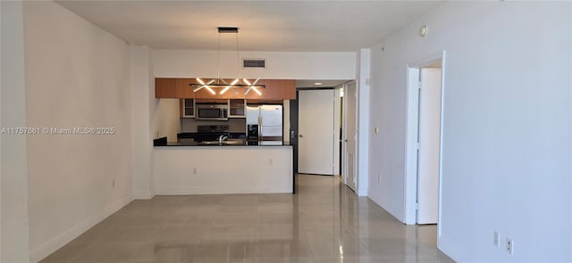 interior space featuring dark countertops, visible vents, baseboards, a peninsula, and stainless steel appliances