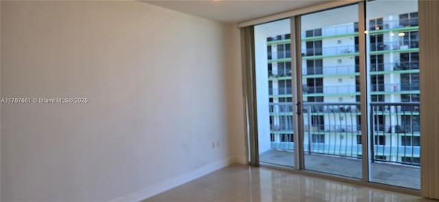 spare room featuring a wall of windows and baseboards