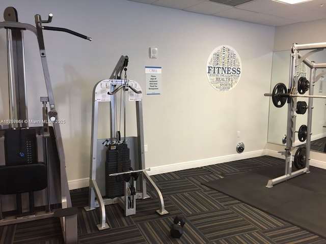 workout area with carpet flooring, baseboards, and a drop ceiling