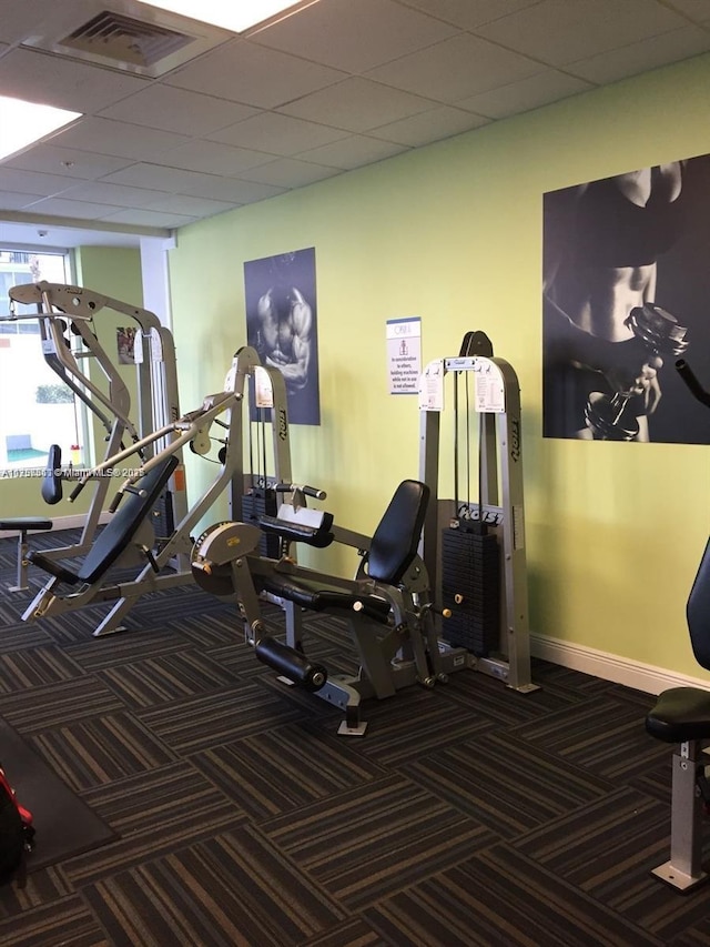 gym with baseboards, visible vents, carpet floors, and a paneled ceiling