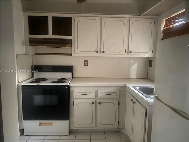 kitchen with under cabinet range hood, light countertops, freestanding refrigerator, electric stove, and a sink