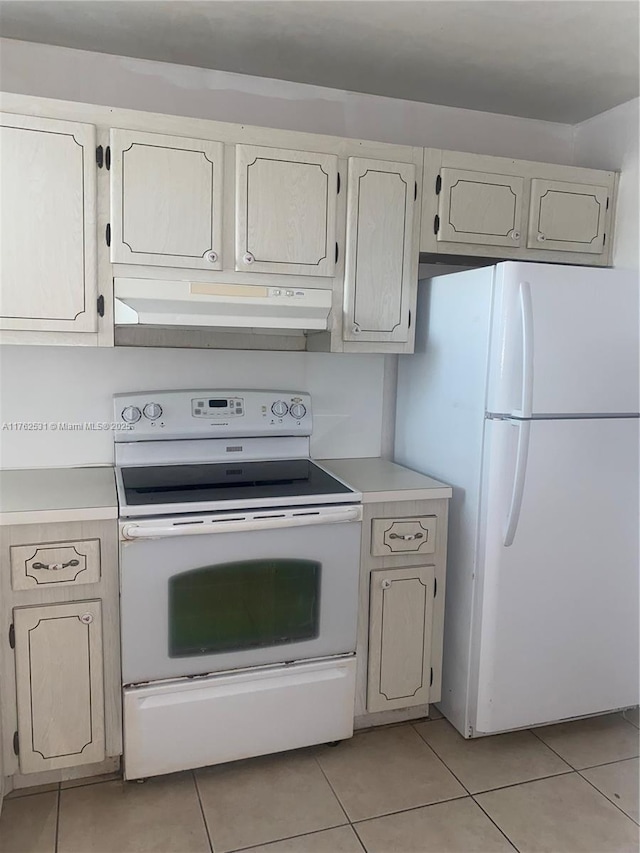 kitchen with under cabinet range hood, white appliances, light tile patterned flooring, and light countertops