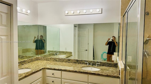 bathroom with double vanity, a shower stall, and a sink