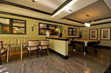 bar featuring visible vents, a tray ceiling, wood finished floors, crown molding, and baseboards