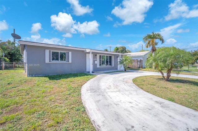 ranch-style home with curved driveway, fence, a front lawn, and stucco siding