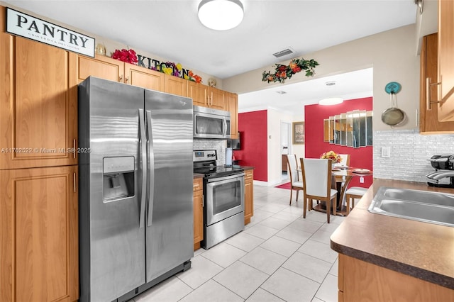 kitchen featuring visible vents, a sink, tasteful backsplash, stainless steel appliances, and light tile patterned floors