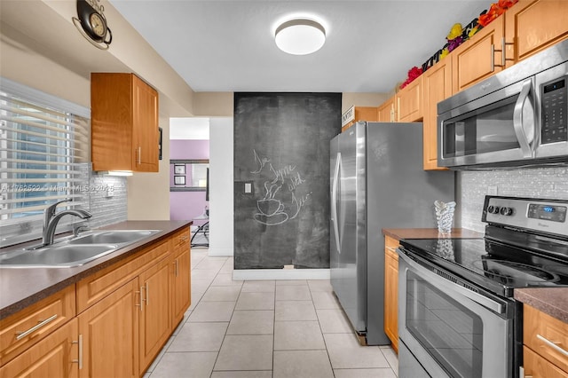 kitchen featuring dark countertops, light tile patterned floors, appliances with stainless steel finishes, and a sink