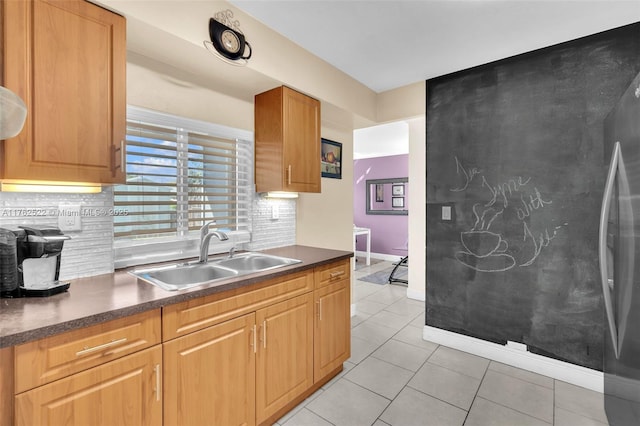 kitchen with a sink, backsplash, dark countertops, and light tile patterned floors