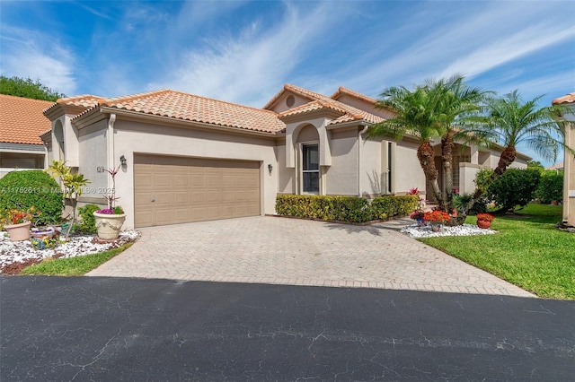 mediterranean / spanish-style home featuring stucco siding, a tile roof, and a garage