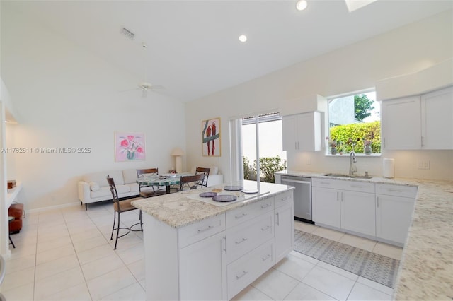 kitchen featuring light tile patterned flooring, a sink, a kitchen island, and stainless steel dishwasher