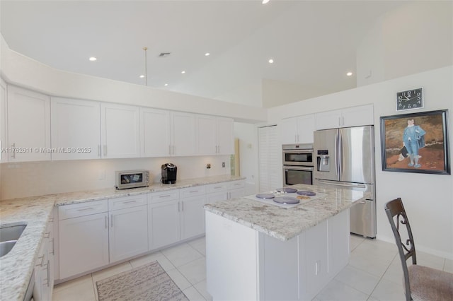 kitchen with white cabinets, light stone countertops, a kitchen island, and stainless steel appliances