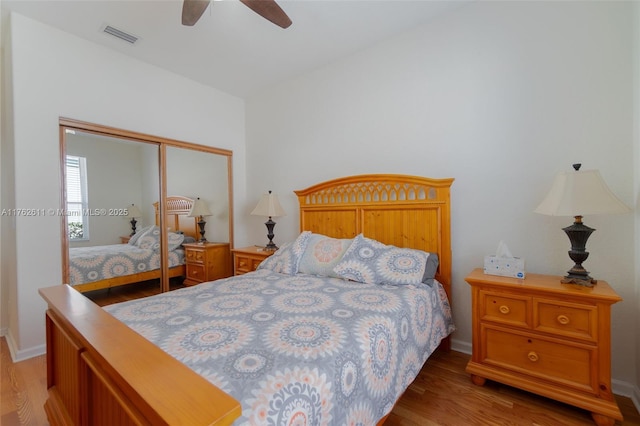 bedroom with a closet, light wood-style floors, visible vents, and ceiling fan