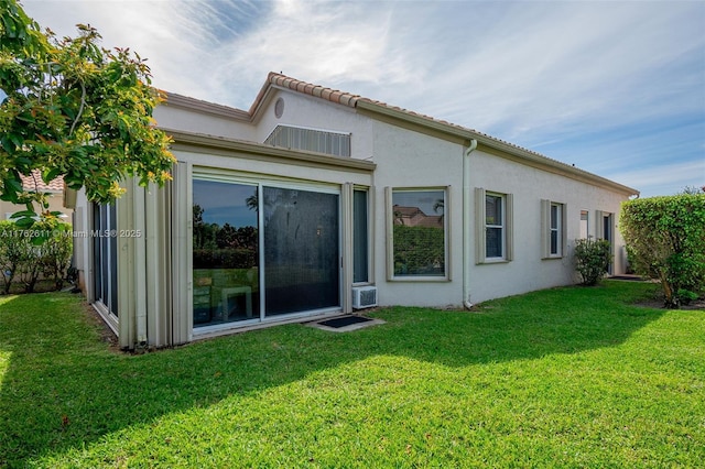 rear view of house featuring stucco siding and a yard