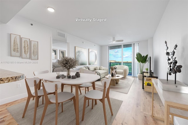 dining room with a wall of windows, a ceiling fan, visible vents, baseboards, and light wood-style floors