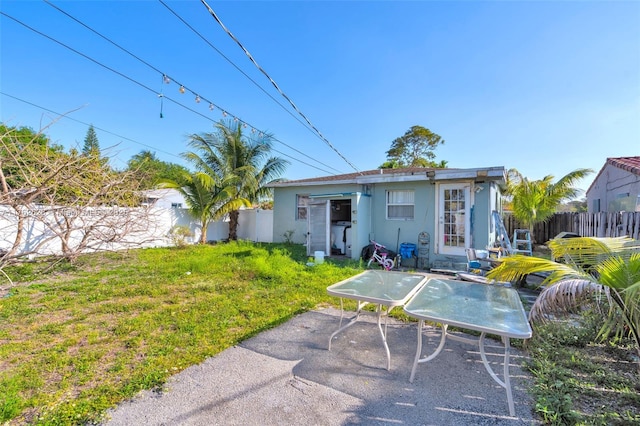 back of property featuring stucco siding, an outbuilding, a fenced backyard, and a yard