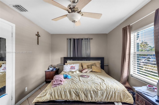 bedroom featuring light tile patterned floors, visible vents, baseboards, and ceiling fan