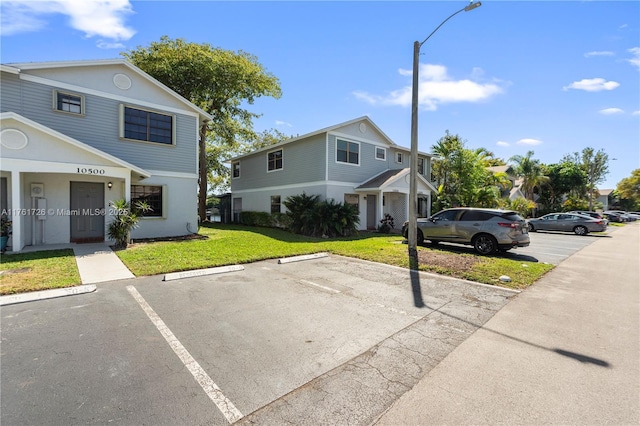 view of property featuring uncovered parking and a front lawn