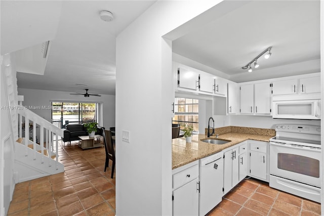 kitchen with white appliances, a ceiling fan, light stone countertops, a sink, and white cabinetry