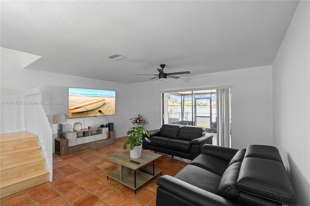 living room featuring stairs, a ceiling fan, and visible vents