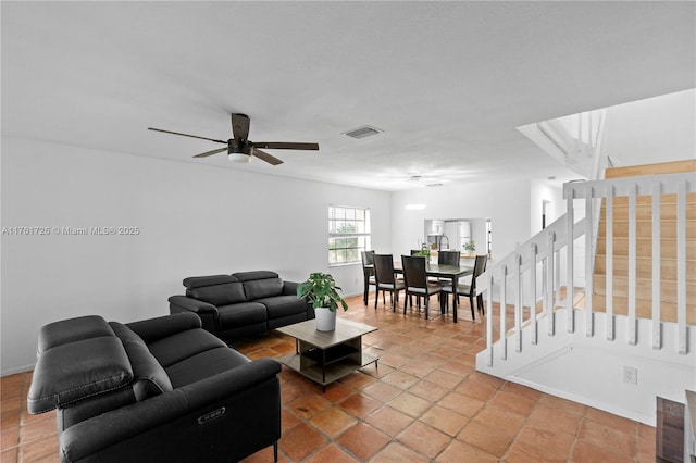 living room with visible vents, baseboards, stairs, and a ceiling fan