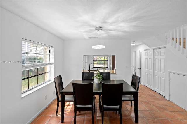 tiled dining space with stairs, baseboards, visible vents, and a sink