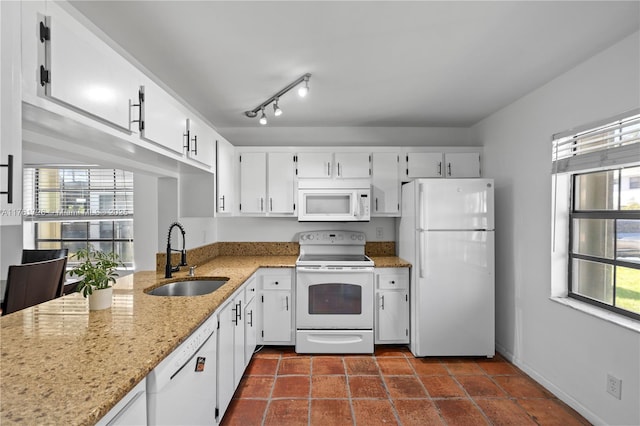 kitchen with track lighting, light stone countertops, white appliances, white cabinetry, and a sink