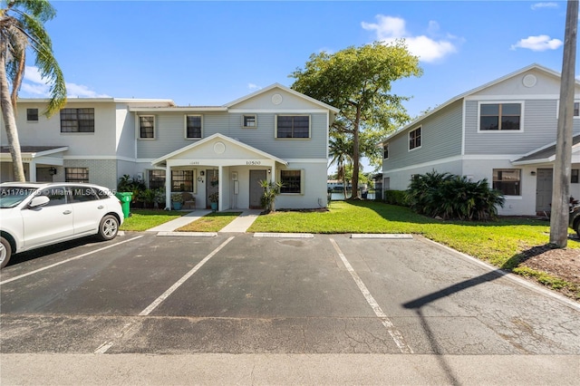 view of property with a front yard and uncovered parking