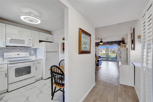 kitchen featuring backsplash, light countertops, white cabinets, white appliances, and marble finish floor