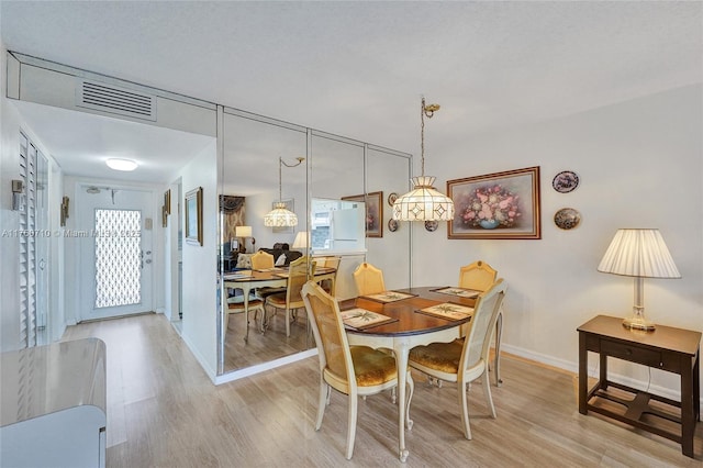 dining room featuring light wood-style floors, visible vents, and a healthy amount of sunlight