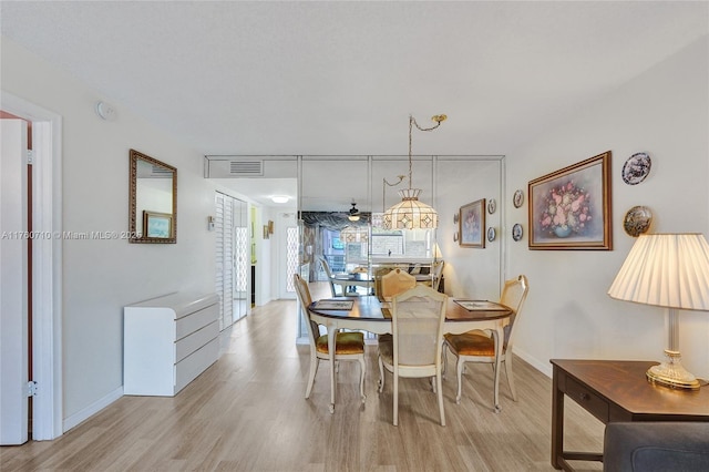 dining space with light wood-style flooring, baseboards, and visible vents