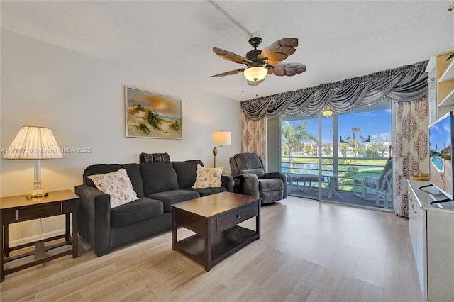 living area featuring light wood finished floors, a textured ceiling, and ceiling fan