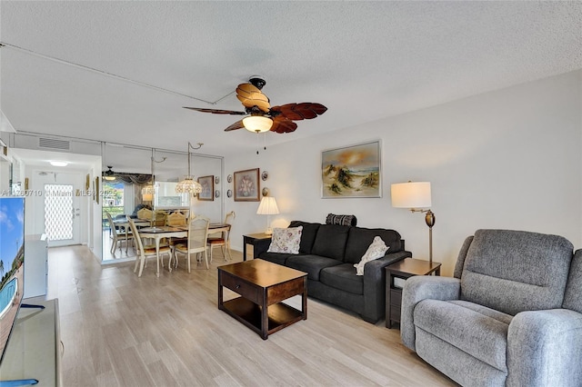 living area with light wood-style floors, a ceiling fan, and a textured ceiling