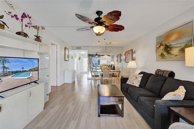 living room with light wood finished floors, visible vents, and ceiling fan