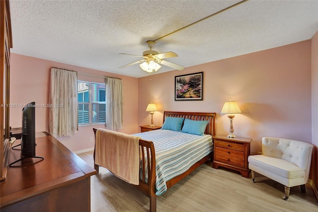 bedroom featuring baseboards, a textured ceiling, a ceiling fan, and wood finished floors