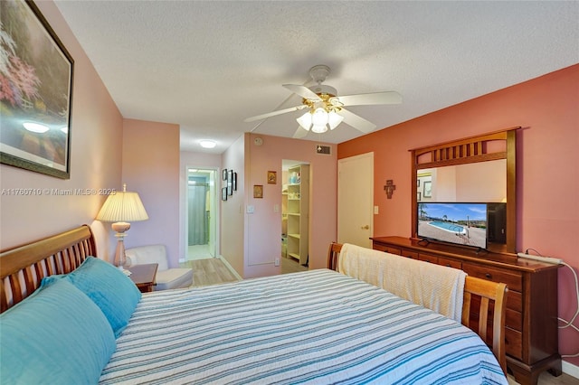 bedroom featuring visible vents, a ceiling fan, a textured ceiling, ensuite bath, and baseboards