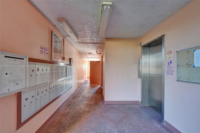 hall with mail area, elevator, a textured ceiling, and baseboards