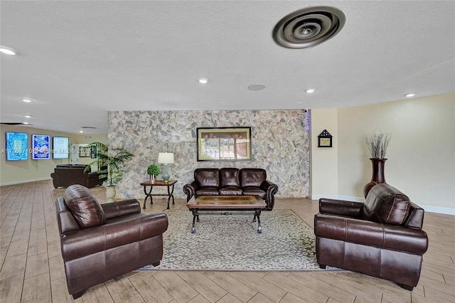 living area with visible vents, baseboards, a textured ceiling, and wood finished floors