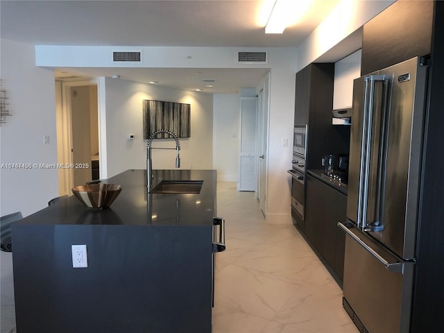 kitchen featuring visible vents, a sink, stainless steel appliances, dark countertops, and marble finish floor