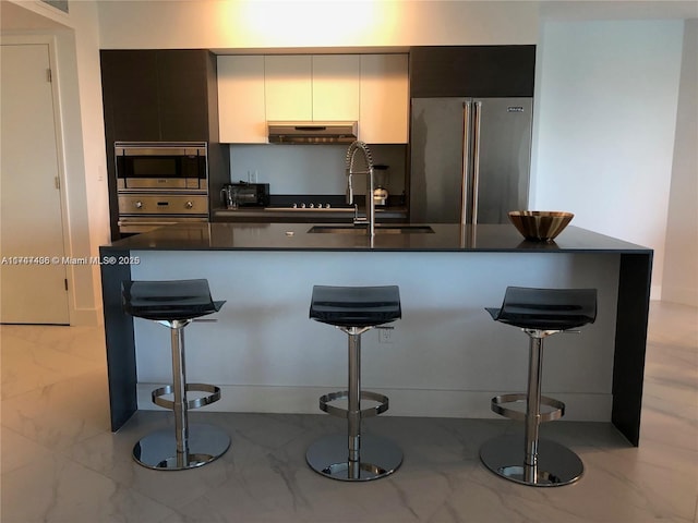 kitchen with stainless steel appliances, a kitchen bar, and dark countertops