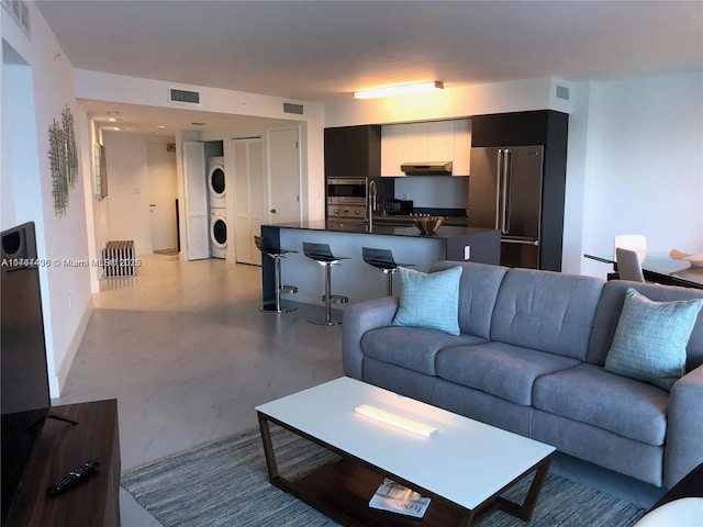 living room with visible vents and stacked washer and clothes dryer