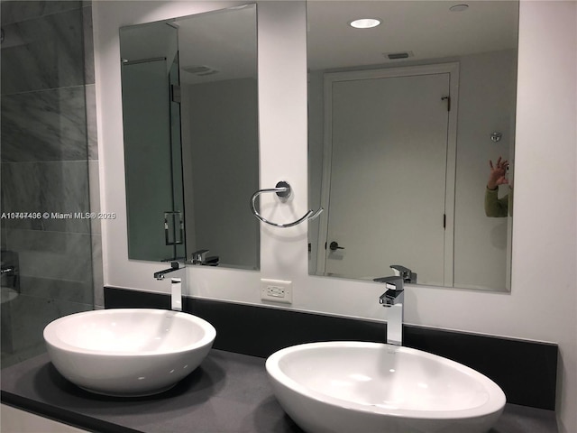 bathroom with a sink, visible vents, recessed lighting, and a tile shower