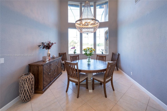 dining space with an inviting chandelier, light tile patterned floors, and baseboards