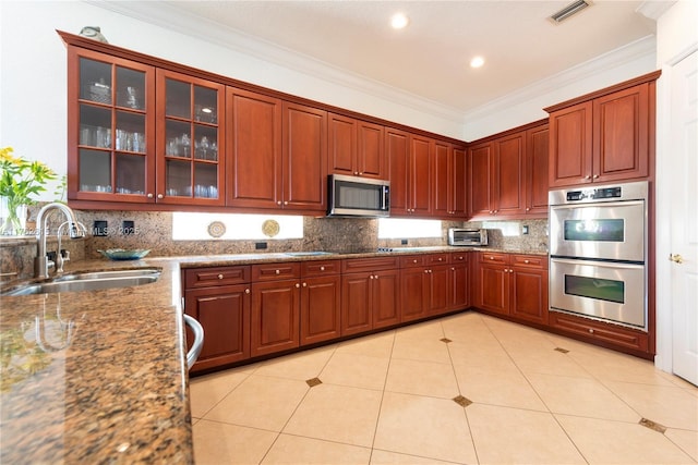 kitchen featuring a sink, stainless steel appliances, crown molding, light tile patterned floors, and decorative backsplash