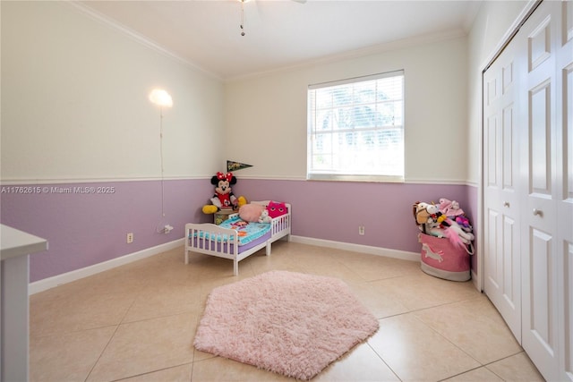 bedroom with tile patterned floors, a closet, baseboards, and crown molding